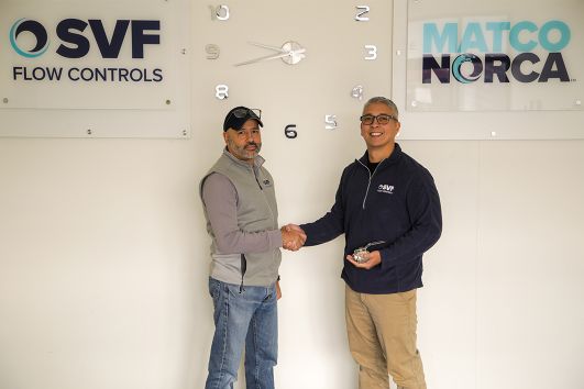 Two men shaking hands, one holding a valve